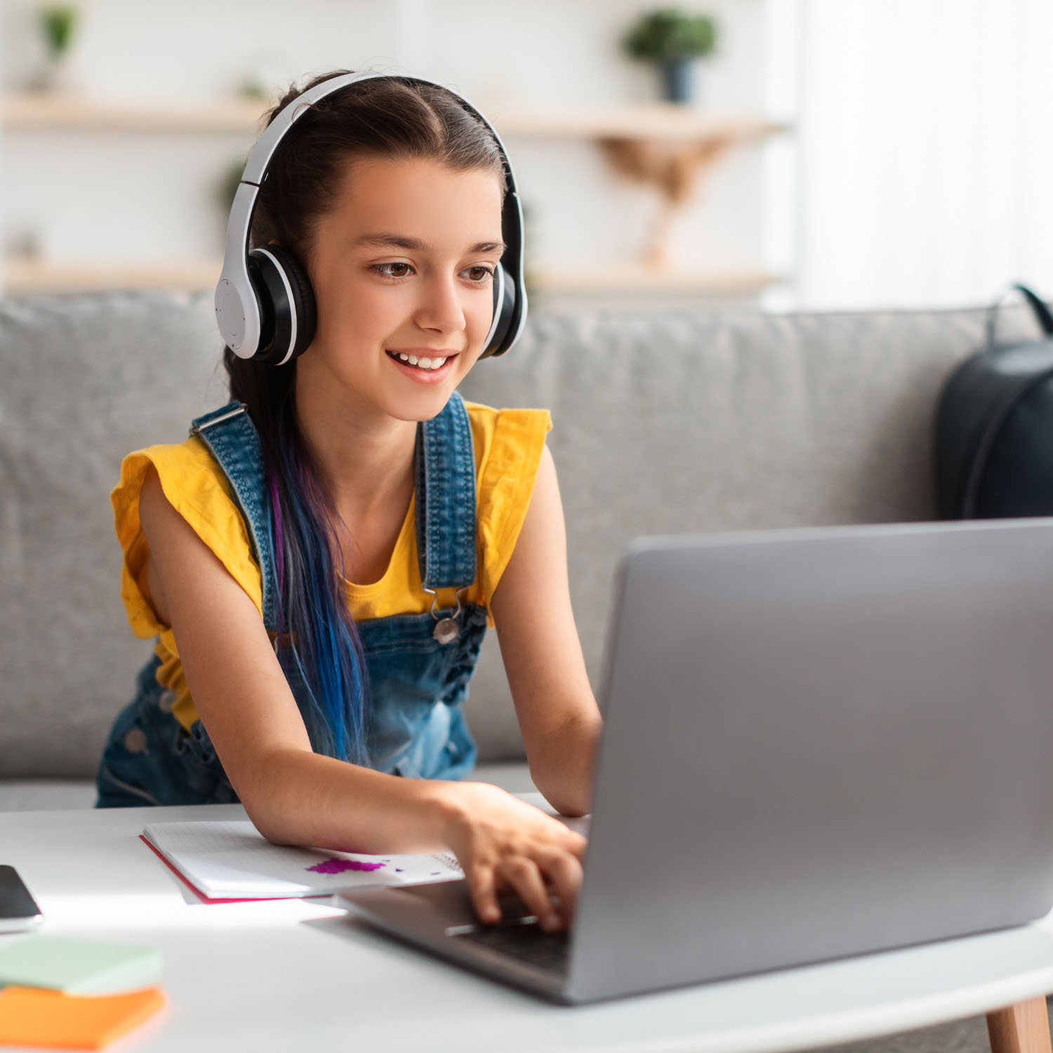 Una niña con auriculares y usando una computadora.